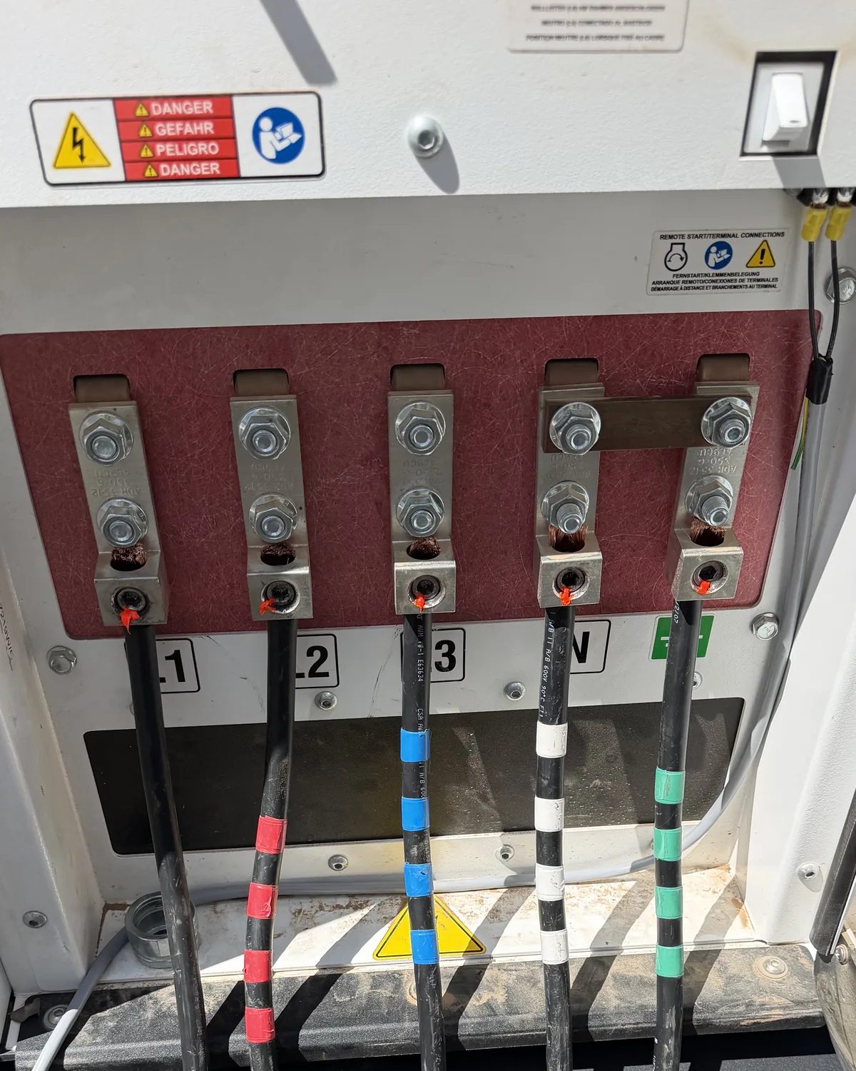 Switchgear interior showing a red phase barrier, large conductors and phase-taped terminations