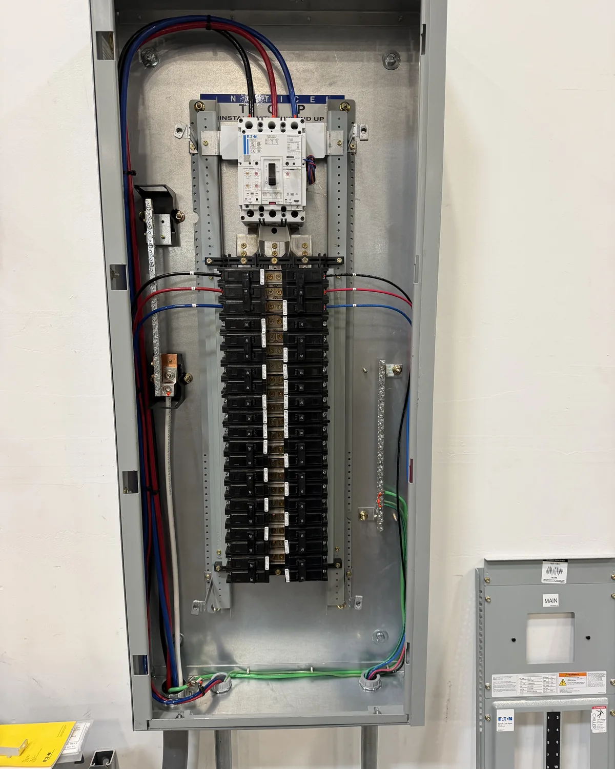 A newly installed panelboard with its door open, showing branch breakers and neatly dressed circuit conductors